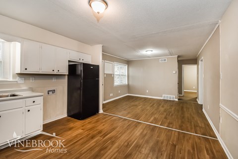 A kitchen with white cabinets and a black fridge is shown.