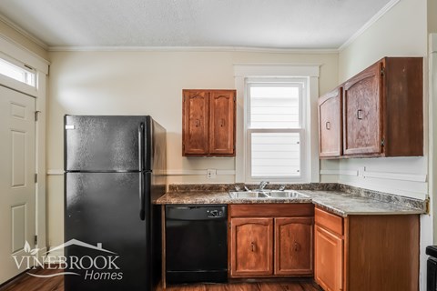 A kitchen with a black fridge and wooden cabinets.