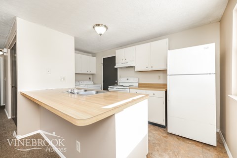 A kitchen with a wooden counter top and white appliances.