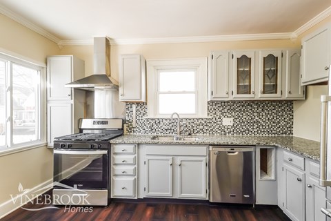 A kitchen with white cabinets and a black and white tiled backsplash.