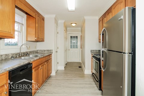 A kitchen with wooden cabinets and a stainless steel refrigerator.