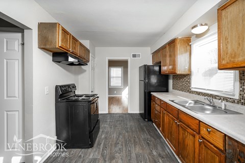 A kitchen with black appliances and wooden cabinets.