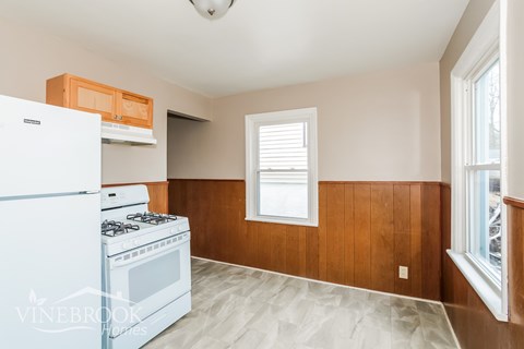 A kitchen with a white stove and wooden walls.