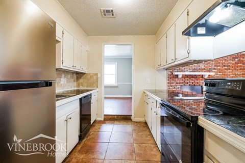 A kitchen with a stainless steel refrigerator and black oven.