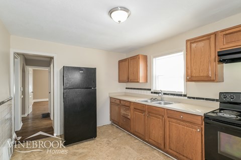 A kitchen with wooden cabinets and a black refrigerator.