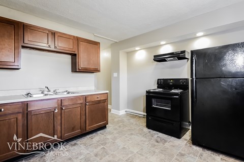 A kitchen with wooden cabinets and a black refrigerator.