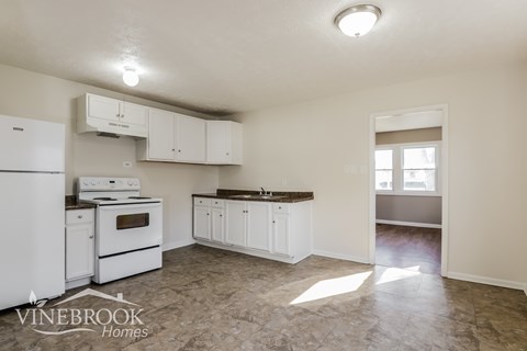 A kitchen with white appliances and cabinets is on the market.