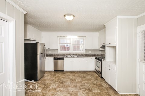 A kitchen with a black refrigerator and white cabinets.