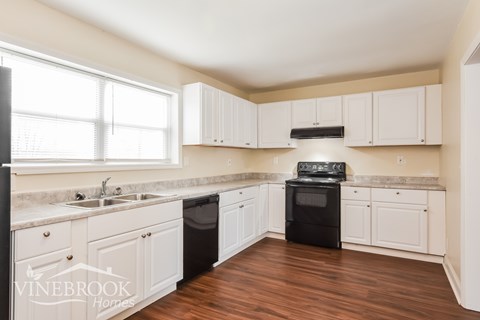 A kitchen with white cabinets and a black stove top oven.