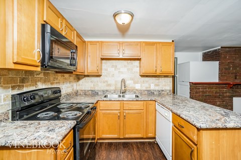 A kitchen with wooden cabinets and a granite countertop.