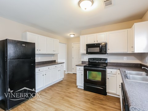 A kitchen with black appliances and white cabinets.