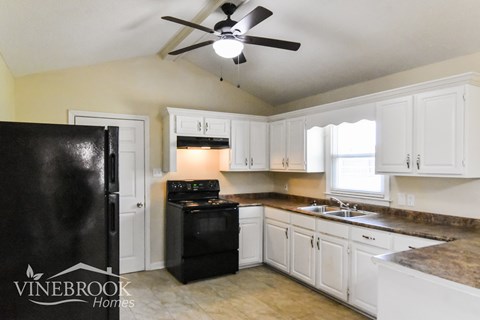 A kitchen with black appliances and white cabinets.