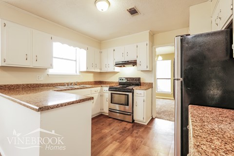 A kitchen with white cabinets and a black refrigerator.