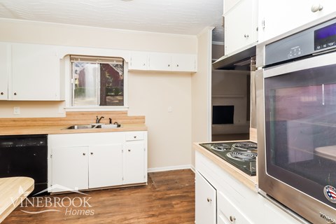 A kitchen with white cabinets and a stainless steel oven.
