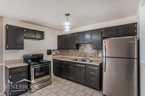 A kitchen with black cabinets and stainless steel appliances.