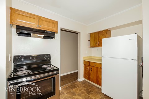 A kitchen with a stove top oven and a refrigerator.