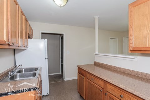 A kitchen with wooden cabinets and a white fridge.