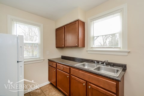 A kitchen with brown cabinets and a white refrigerator.