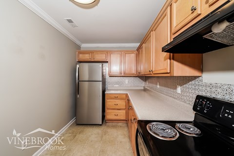 A kitchen with a black stove top oven and a silver refrigerator.