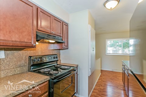 A kitchen with a black stove top oven and wooden cabinets.