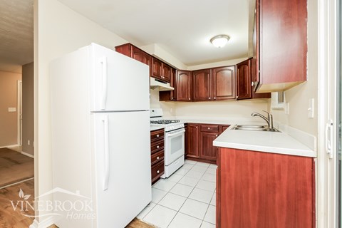 A kitchen with white appliances and brown cabinets.