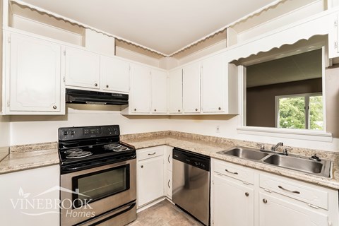 A kitchen with white cabinets and a black stove top oven.