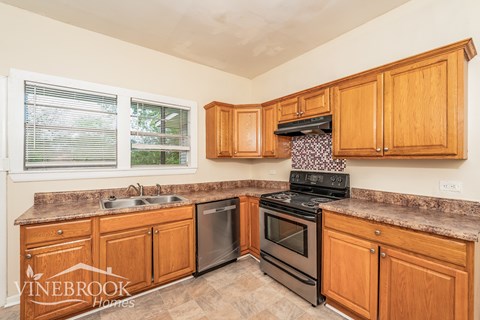 A kitchen with wooden cabinets and a black stove top oven.