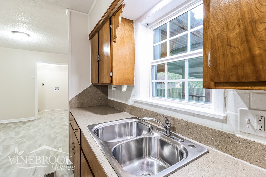 A kitchen with a sink and wooden cabinets.