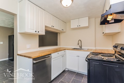 A kitchen with white cabinets and a black stove top.