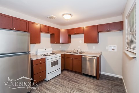 A kitchen with brown cabinets and a stainless steel refrigerator.