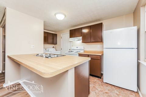 A kitchen with a white refrigerator and wooden countertops.