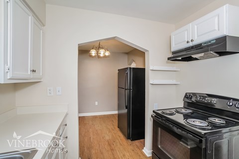A kitchen with a black fridge and stove top oven.