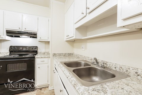 A kitchen with a black stove top oven and a stainless steel sink.