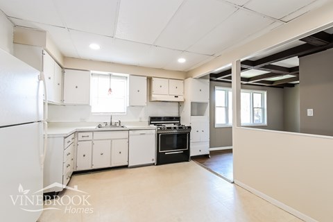 A spacious kitchen with white appliances and cabinets.