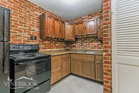 A kitchen with a black stove and wooden cabinets.