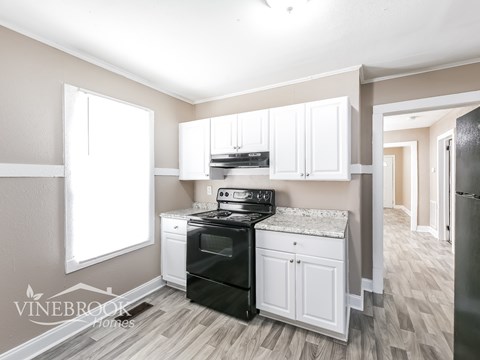 A kitchen with a black stove top oven and white cabinets.