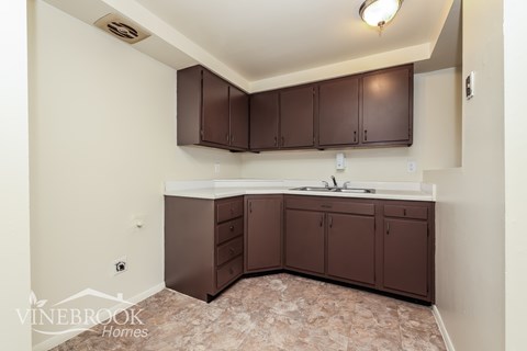 A kitchen with brown cabinets and a marble floor.