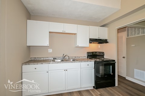 A kitchen with white cabinets and a black stove top oven.