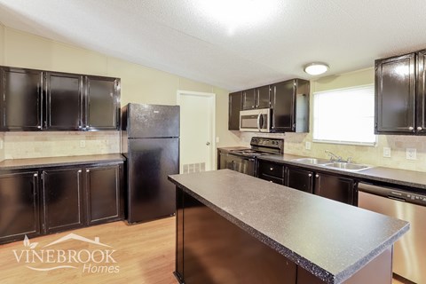A kitchen with black cabinets and a Vinebrook Homes logo.
