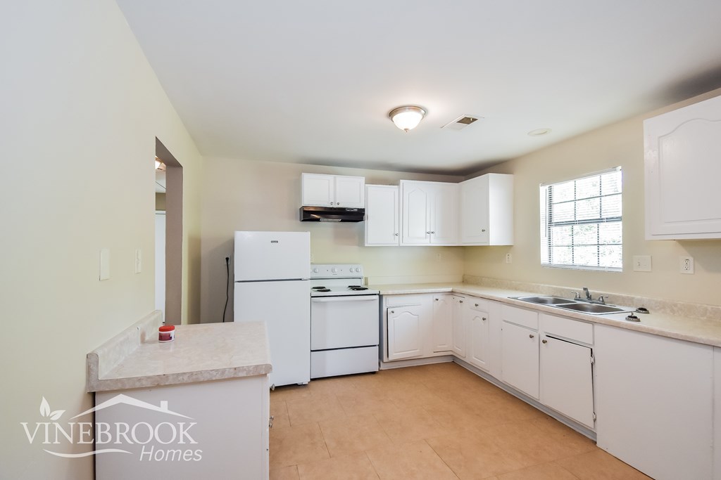 A kitchen with white appliances and cabinets is for sale.