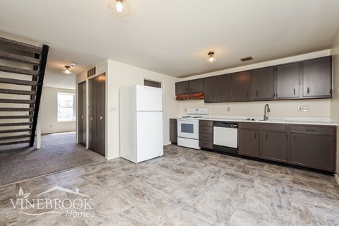 A kitchen with a white refrigerator and brown cabinets.