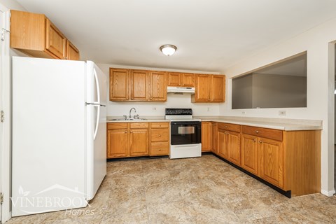 A kitchen with a white fridge and wooden cabinets.