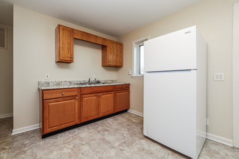 A kitchen with a white refrigerator and wooden cabinets.
