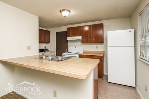 A kitchen with a white refrigerator and wooden cabinets.