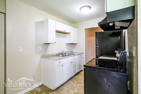 A kitchen with a black oven and white cabinets.