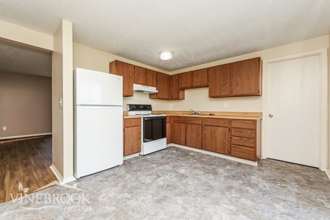 A kitchen with a white refrigerator, wooden cabinets, and a stove top oven.