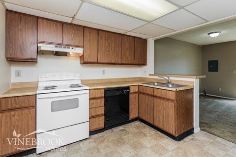 A kitchen with wooden cabinets and a white stove top oven.