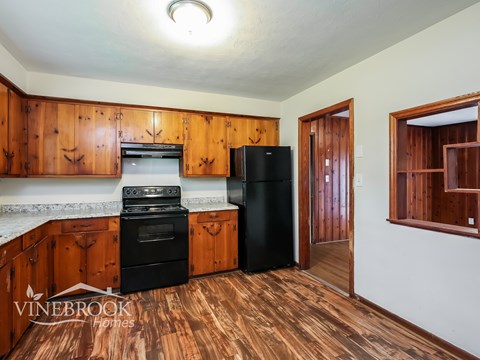 A kitchen with wooden cabinets and a black refrigerator.