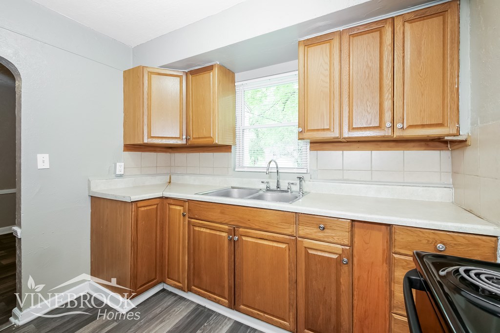 A kitchen with wooden cabinets and a stove top oven.