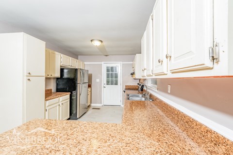 A kitchen with white cabinets and a brown rug on the floor.